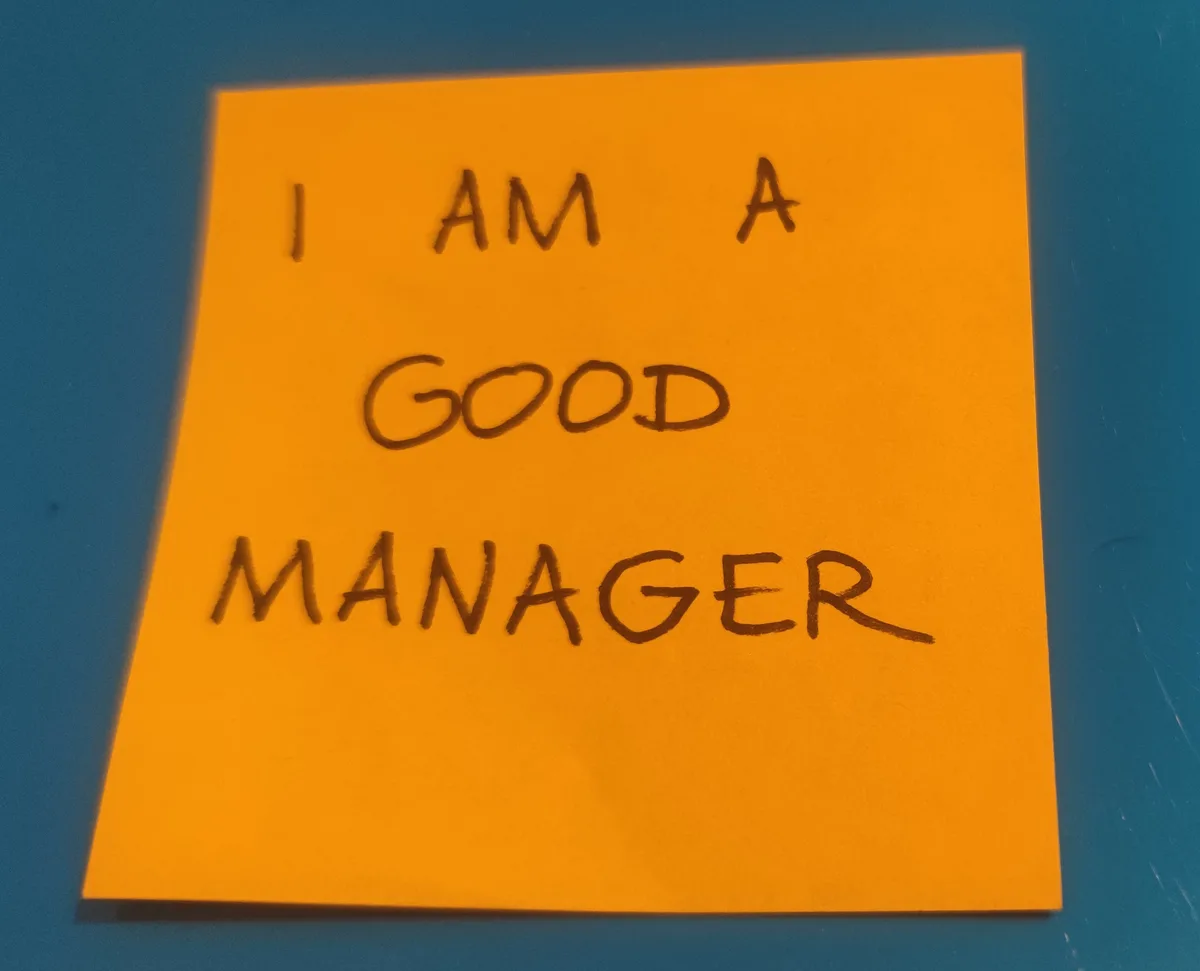 Orange sticky note with "I am a good manager" handwritten on it.